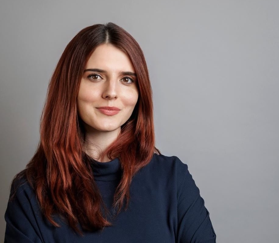 A woman with reddish brown hair in a navy sweater.